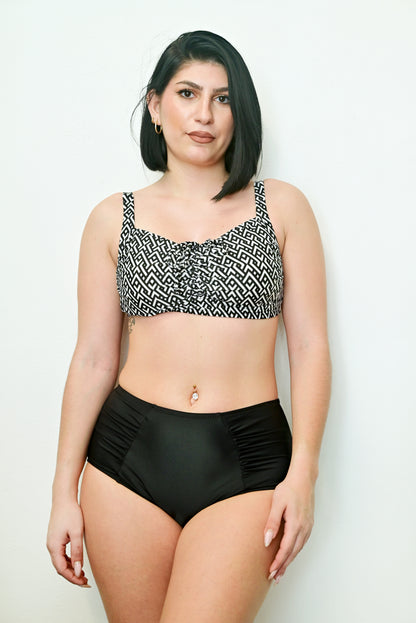 Sunlover swimwear model wearing a black and white patterned bikini top and high-waisted black shorts on a light gray background (Colour: P25)